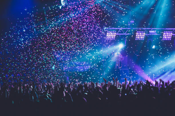 Se puede ver una multitud en un concierto o festival con muchas luces y confetti.