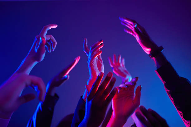 La imagen muestra unas manos en el aire con una ambientación de colores neón, dando la sensación que esas personas están en un festival o una discoteca.