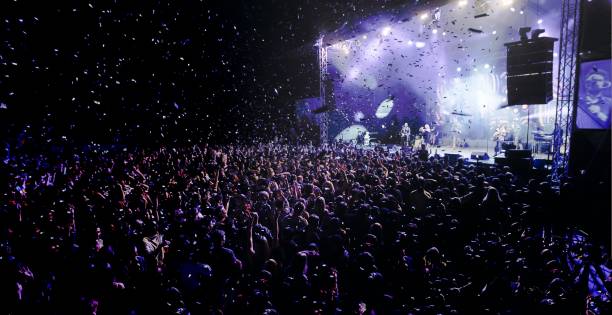 En la imagen es visible un escenario con mucha audiencia y es de noche, están rodeados de confeti