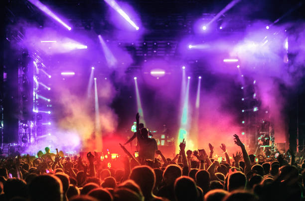 En la imagen se puede observar un concierto o festival a oscuras y con muchas luces y humo, se ve que hay una multitud grande y eufórica