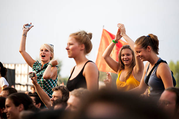 En la imagen se puede ver una multitud en u festival, se enfoca en un  grupo de amigas que están ahí.
