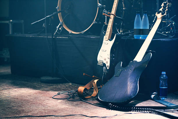 En la imagen se ve unos instrumentos musicales, como una guitarra, un bajo, una batería,.. en un escenario 