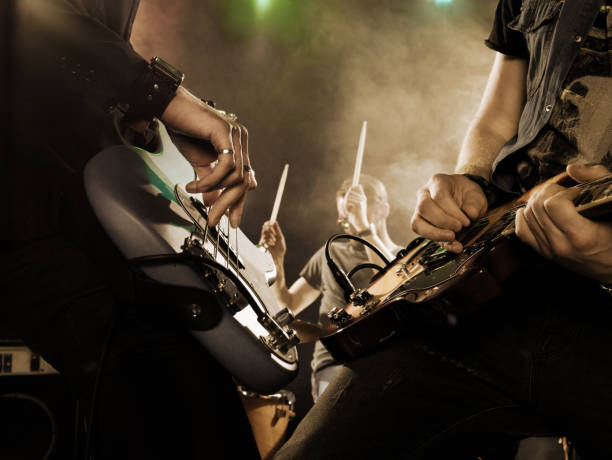 En la imagen se puede ver dos artistas tocando juntos las guitarras. Parece que es un banda tocando en un concierto o festival