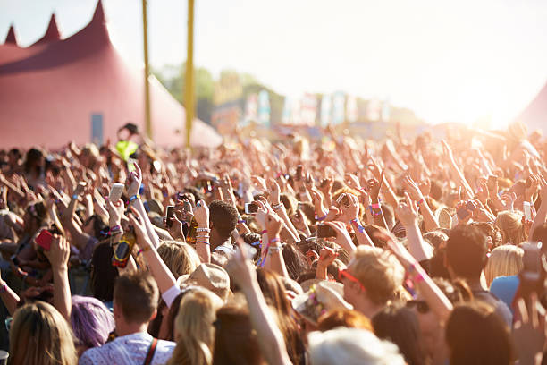 En la fotografía es visible una multitud de gente que está grabando con el móvil lo que están viendo y bailando. Están al aire libre en lo que parece un festival.